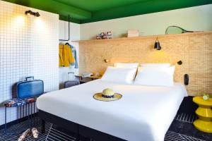 a bedroom with a large white bed with a hat on it at ibis Styles Lyon Meyzieu Arena Stadium in Meyzieu