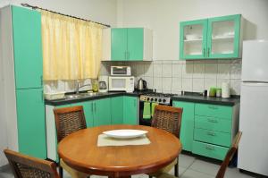 a kitchen with green cabinets and a wooden table at Rachel's Apartments in Paramaribo