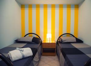two beds in a room with yellow and white stripes at Villalba in Balestrate