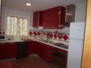 cocina con armarios rojos y nevera blanca en Mirador del Duque, en Güéjar-Sierra