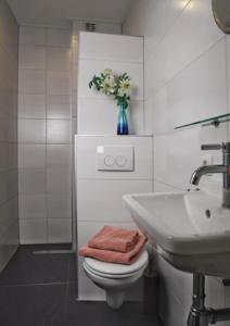 uma casa de banho com um WC, um lavatório e um vaso de flores em B&B Hof 't Sprakel em Haaksbergen
