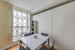 une salle à manger avec une table et des chaises blanches ainsi qu'une fenêtre dans l'établissement ID 308 Châtelet Rivoli, à Paris