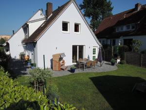 Casa blanca con patio con sillas en Haus Grömitz - Haus Möwenstraße, en Grömitz