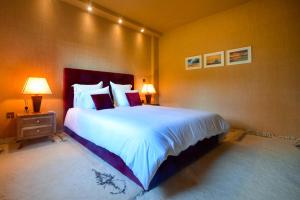 een slaapkamer met een groot bed met witte lakens en kussens bij Luxueuse dépendance avec jardin au bord de l'océan in Rabat