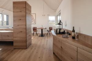 cocina con paredes blancas, suelo de madera y mesa en Winzerhäuser J&A Skringer, en Leutschach