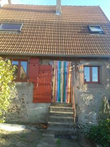 une maison dotée d'une porte rouge avec un rideau coloré. dans l'établissement Les Rosiers, à Eschbourg