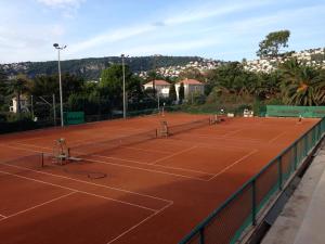una pista de tenis con dos tenistas. en Nyrenoverad lägenhet med havsutsikt en Villefranche-sur-Mer