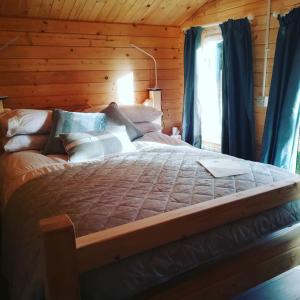 a bedroom with a large bed with blue curtains at Dunmore Gardens Log Cabins in Carrigans