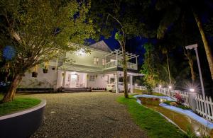 a white house with a driveway at night at Alencherry plantation homestay in Thekkady