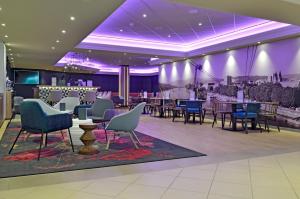 une salle à manger avec des tables, des chaises et un éclairage violet dans l'établissement Mercure Hotel Koblenz, à Coblence