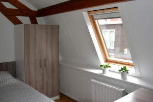 een slaapkamer met een raam en een houten kast bij Short Stay Wageningen in Wageningen