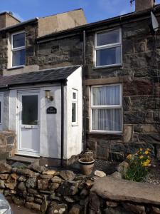 uma casa de pedra com uma porta branca e janelas em Tylwyth em Waenfawr