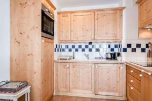 una cocina con armarios de madera y fregadero en Apartment Balmat - Chamonix All Year, en Chamonix-Mont-Blanc