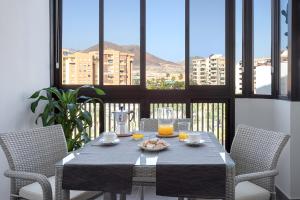 Almar Apartamento en Los Cristianos con AC في لوس كريستيانوس: طاولة مع كرسيين وطاولة مع عصير برتقال