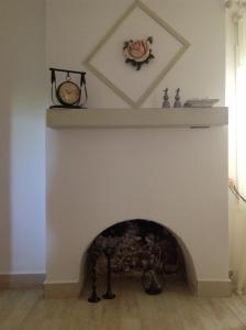 a fireplace with a white mantle with a clock on it at Losta Sahil Evi 2 in Selimiye