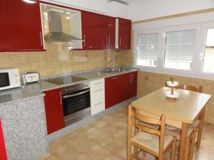 a kitchen with red cabinets and a wooden table at Casa Lourdes in Corcubión