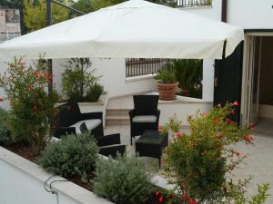 un ombrellone bianco su un patio con sedie e fiori di Il Giardino Delle Sete a Mesagne