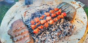 a bunch of food on a grill with tongs at Guest House Buba in Ushguli