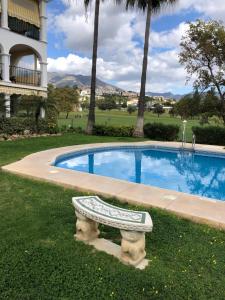 uma piscina com um banco ao lado de um edifício em La Siesta de Mijas Golf 174 em Fuengirola