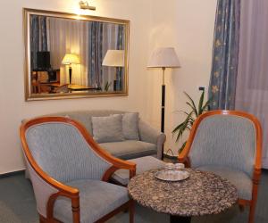 ein Wohnzimmer mit einem Sofa, einem Tisch und Stühlen in der Unterkunft Hotel Central in Nagykanizsa