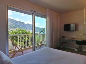 a bedroom with a bed and a view of a balcony at Hotel Palm Garavan in Menton