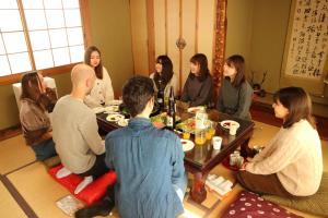 a group of people sitting around a table eating at Hostel Jumpu Manpan in Otaru