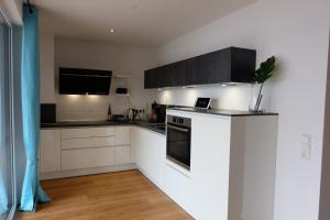 a kitchen with white cabinets and a laptop on the counter at Boutique Appartement @Park in Rheinhausen