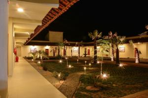 a courtyard with palm trees and lights at night at Hotel Ribeira dos Icós in Icó