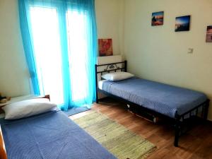 two beds in a room with a large window at Aspa's Apartment in Kavála