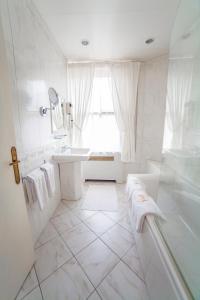 a white bathroom with a tub and a sink at Hotel Meurice in Calais +47 photos
