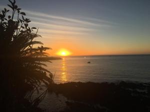 a sunset over the ocean with the sun setting at A Villa by the Sea Bed & Breakfast in Vila Franca do Campo