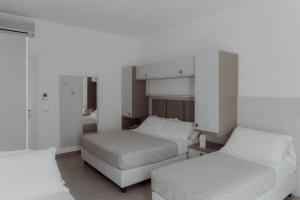 2 camas en una habitación con paredes blancas en Hotel Caravel, en Vasto
