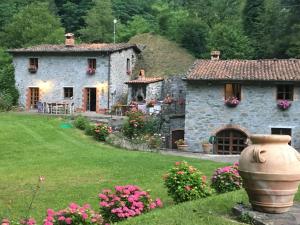 una casa de piedra con un jarrón grande delante de ella en Relax totale nel Bosco Lucca, en Ghivizzano