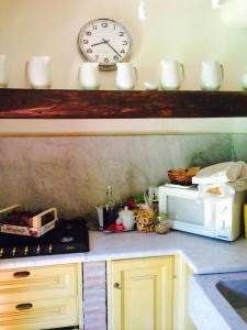 a kitchen with a microwave and a clock on the wall at Relax totale nel Bosco Lucca in Ghivizzano