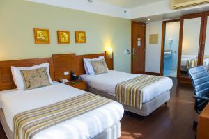 a hotel room with two beds and a chair at Quality Porto Alegre in Porto Alegre