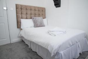 a bedroom with a large white bed with a large headboard at TLK Apartments & Hotel - Beckenham in Beckenham