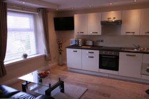 a kitchen with white cabinets and a table at The Thomas Suite in Llandudno +13 photos