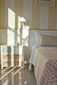 a white bedroom with a bed and a night stand at Glamroom Vatican Apartment in Rome
