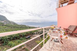 ein Balkon eines Hauses mit einem Tisch und Stühlen in der Unterkunft Casa Annie in Arco da Calheta