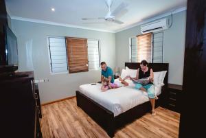 mężczyzna i kobieta siedzący na łóżku z dzieckiem w obiekcie Platinum Cawa Apartments w mieście Nadi