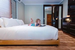 a little girl sitting on top of a bed at Platinum Cawa Apartments in Nadi