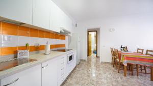 une cuisine avec des armoires blanches et une table avec des chaises dans l'établissement Armonía Beach 104, à Arinaga