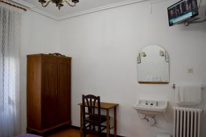 a bathroom with a toilet, sink, and mirror at HOSTAL OVIEDO in León