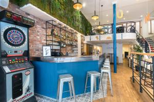 un bar avec un jeu de fléchettes et des tabourets dans l'établissement Hotel The Playce by Happyculture, à Paris