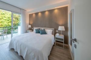 a bedroom with a large white bed and a balcony at Italia Living Villa in Padenghe sul Garda +22 photos