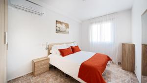 Un dormitorio blanco con una cama grande con almohadas rojas en Armonía Beach 17, en Arinaga