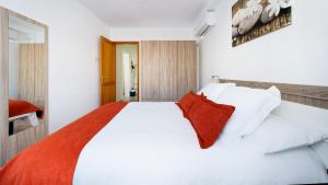 a bedroom with a white bed with a red pillow at Armonía Beach 17 in Arinaga