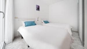 two white beds in a white room with blue pillows at Armonía Beach 17 in Arinaga