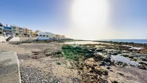 a beach with rocks and the ocean and buildings at Armonía Beach 17 in Arinaga