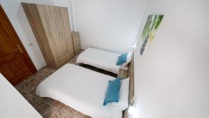 two beds in a small room with blue pillows at Armonía Beach 17 in Arinaga